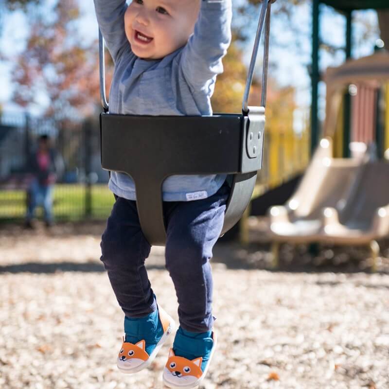 Toddler boy in swing wearing Fox shoes