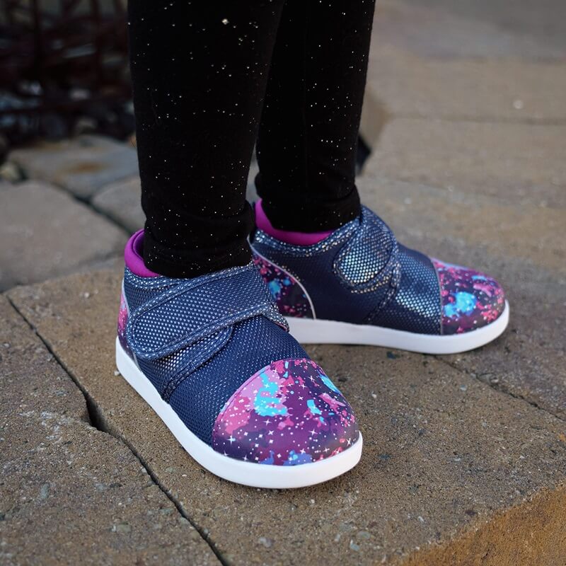 Child standing on pavement wearing Nebula shoes