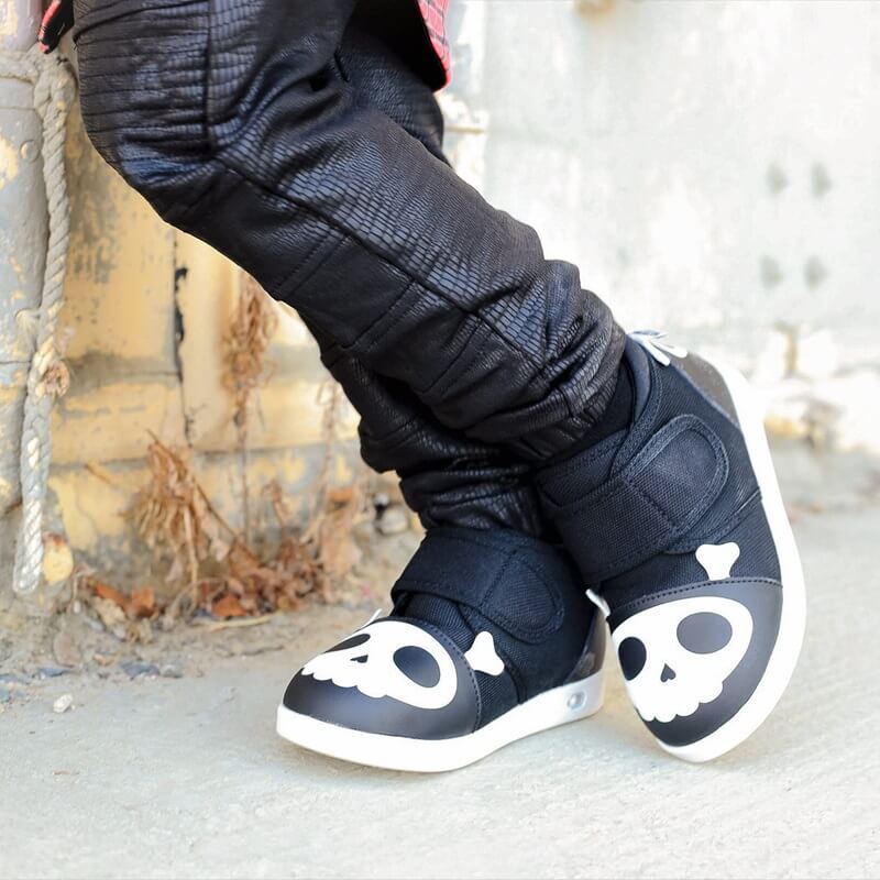 Child leaning on wall wearing Skull shoes